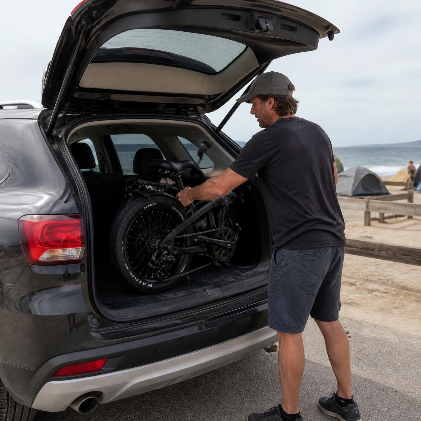 Folded electric bike loaded into the back of an SUV at the beach