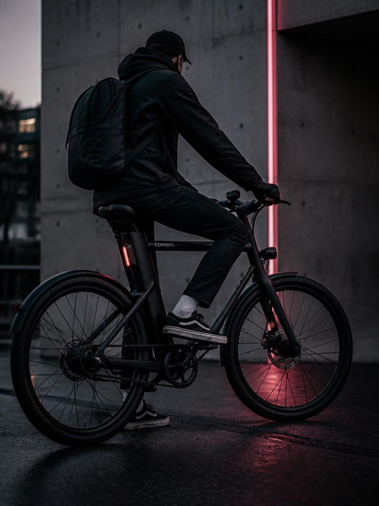 Rider on an electric commuter city bike against concrete at dusk